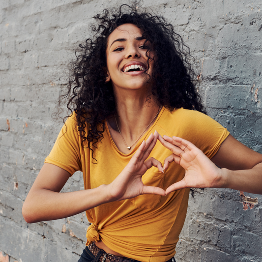 happy lady doing a heart to match her smile to point how important is the journey of self love