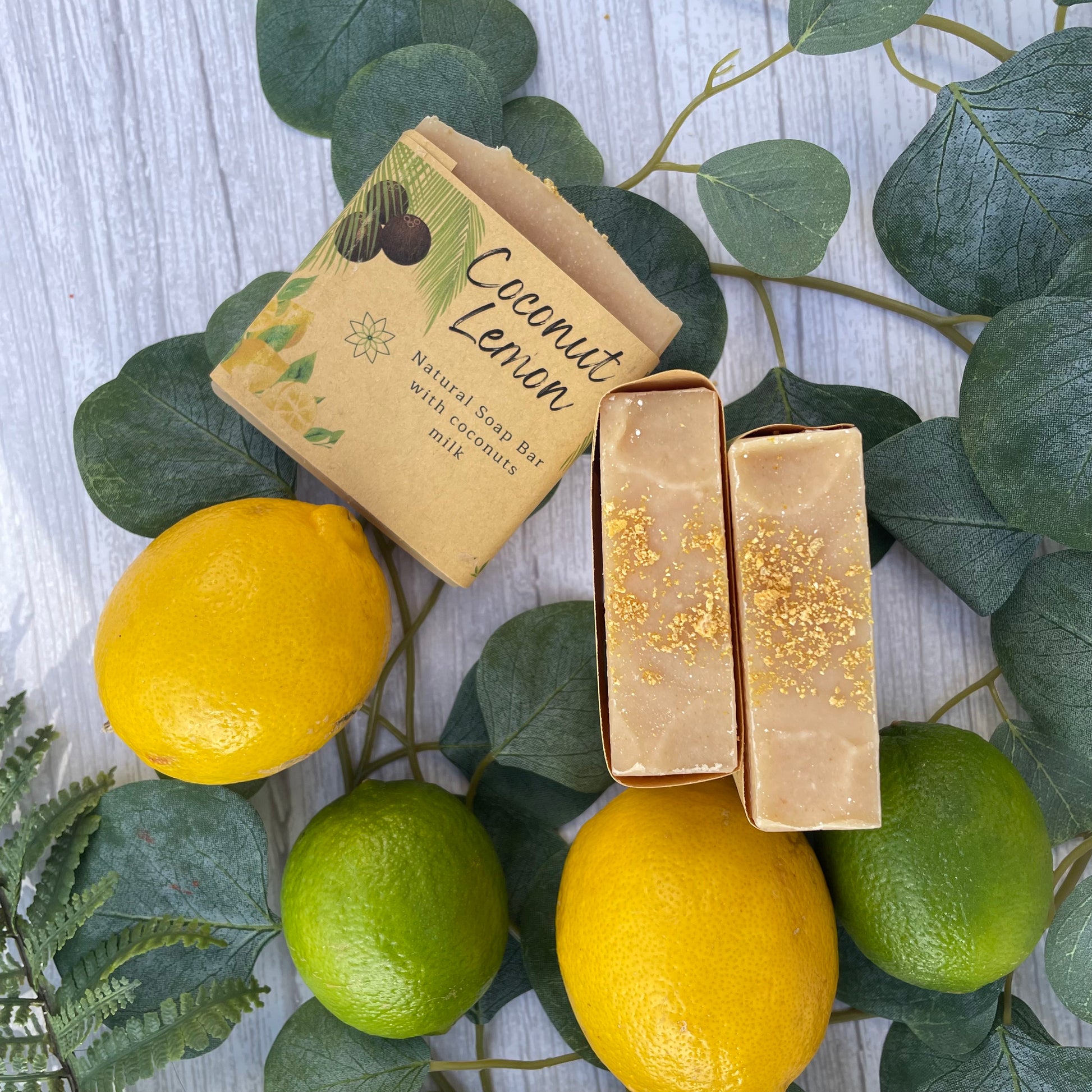 3 handcrafted vegan soaps, one showing the front label and 2 showing the beautiful top with lemon peel. the picture has green and yellow lemons to highlight the zesty and tropical vibe 