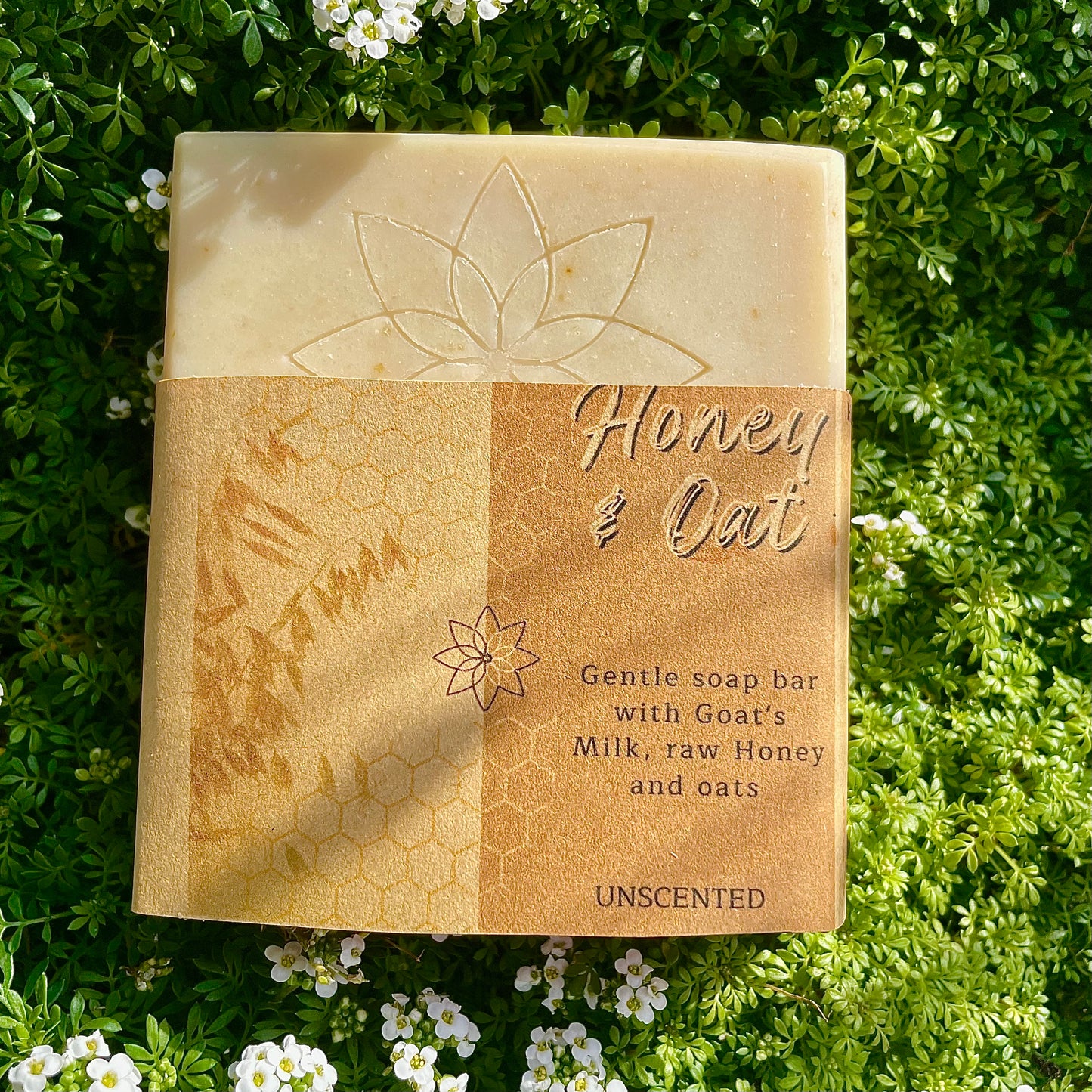 Honey and Oat fragrance free soap, showing design of the soap and the label, front side. on a bed of wild flowers